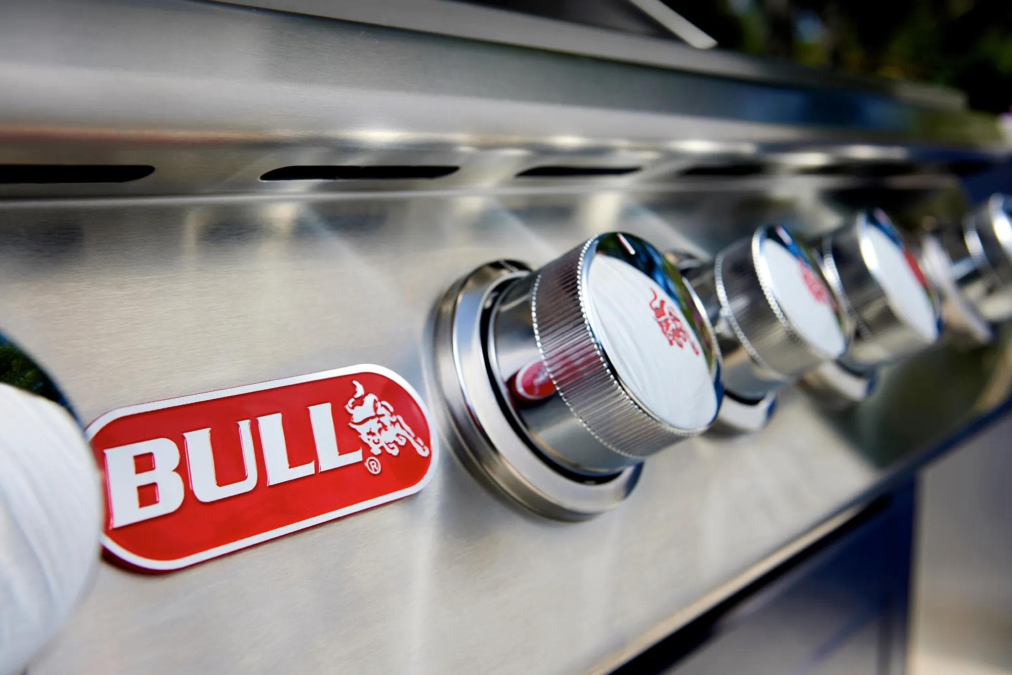 Bull stainless-steel grill installed in a backyard outdoor entertaining space at dusk.
