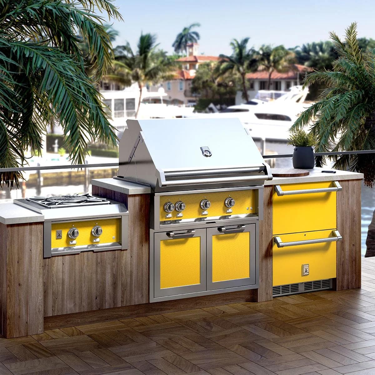 Lifestyle scene of a Hestan Newport outdoor cooking suite installed on a coastal patio with grill and side burners.