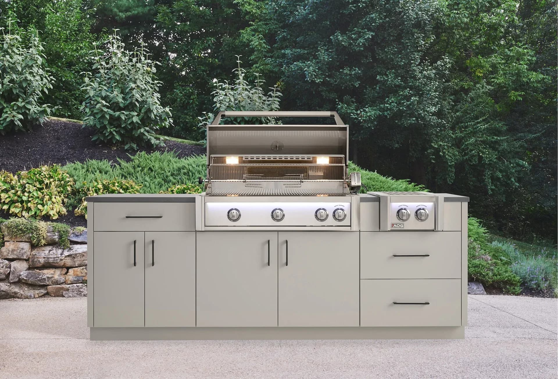 American Outdoor Grill L-Series built into a stone outdoor kitchen island with interior halogen lights on