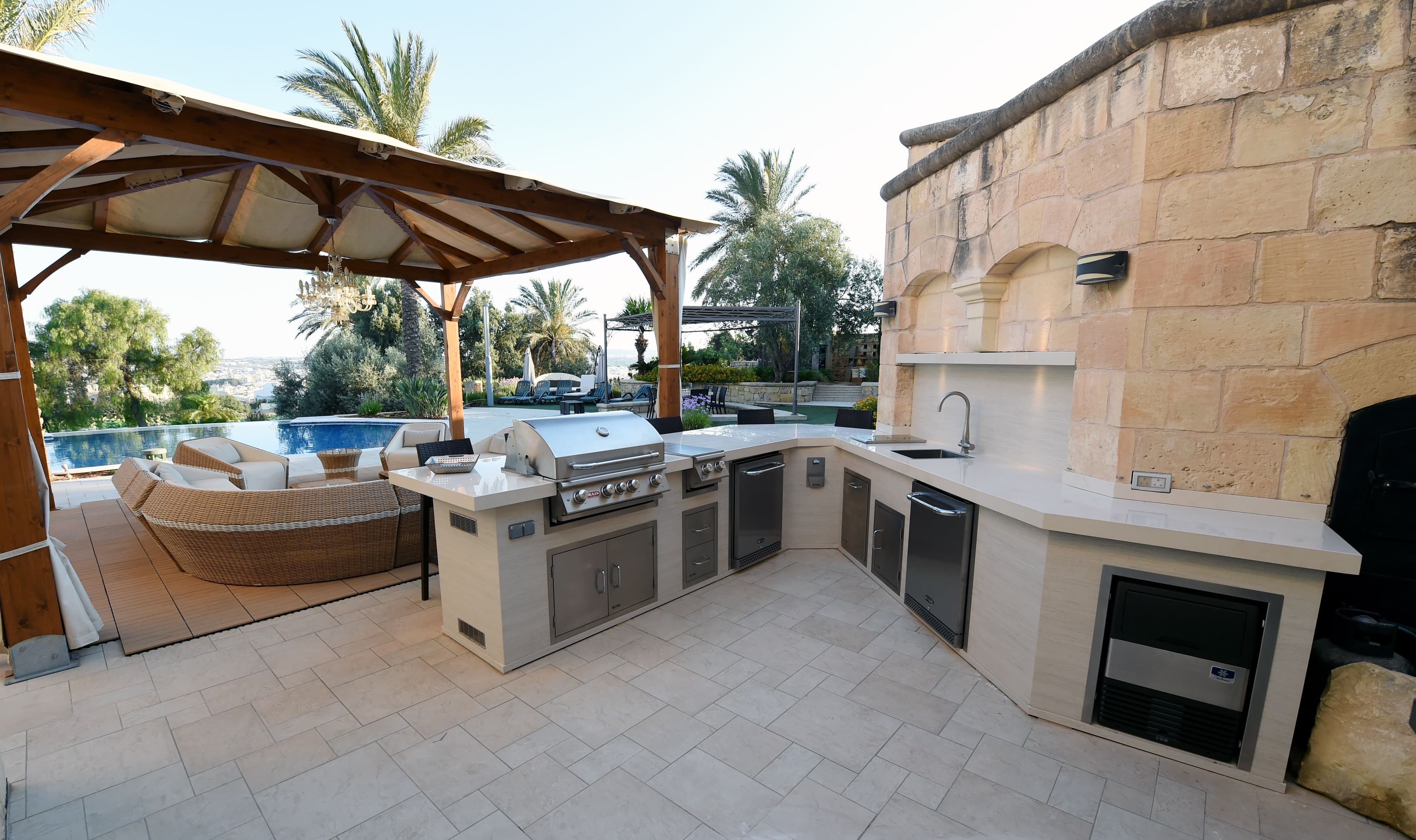 Heavy-duty grill cover installed over a built-in grill and backsplash with cinch straps secured and mesh vents visible on the side panel.